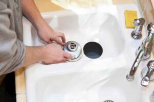 Man installing garbage disposal in home.