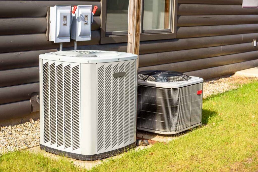 Heating and air conditioning system external units on grass in a house backyard.
